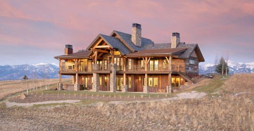 Exterior of a two story timber home with full length covered porch and three chimneys